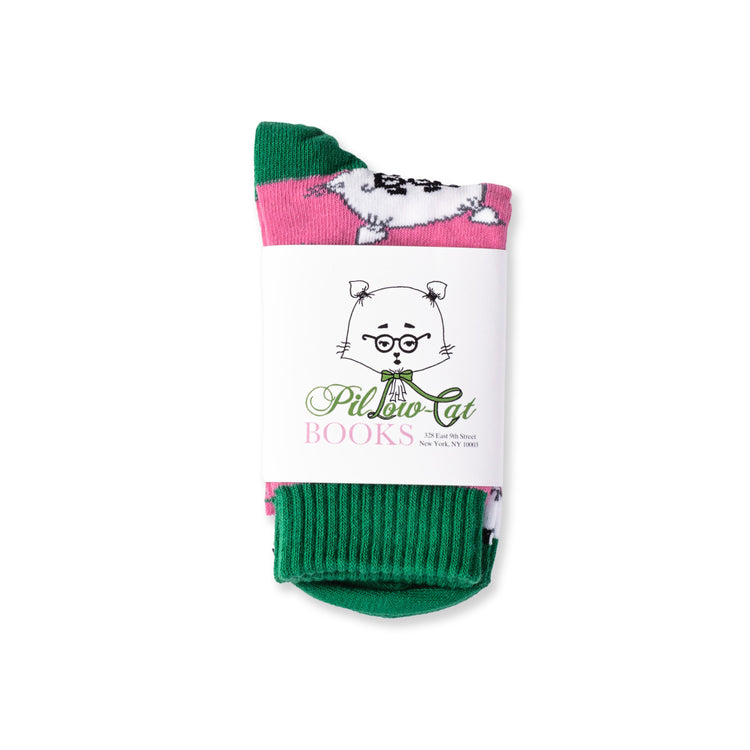 A pair of pink and green socks featuring a repeated pattern of a stylized, cartoon-like cat with glasses and a bow tie packaged in a branded wrap.