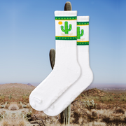 A pair of white socks with green and yellow cactus designs and a small cactus flower detail.