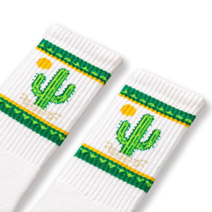 A pair of white socks with green and yellow cactus designs and a small cactus flower detail.
