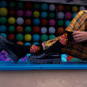 A pair of black socks with a flaming dice design with a carnival background 
